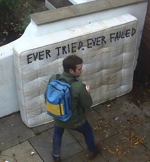 Man covering dumped mattress with graffiti